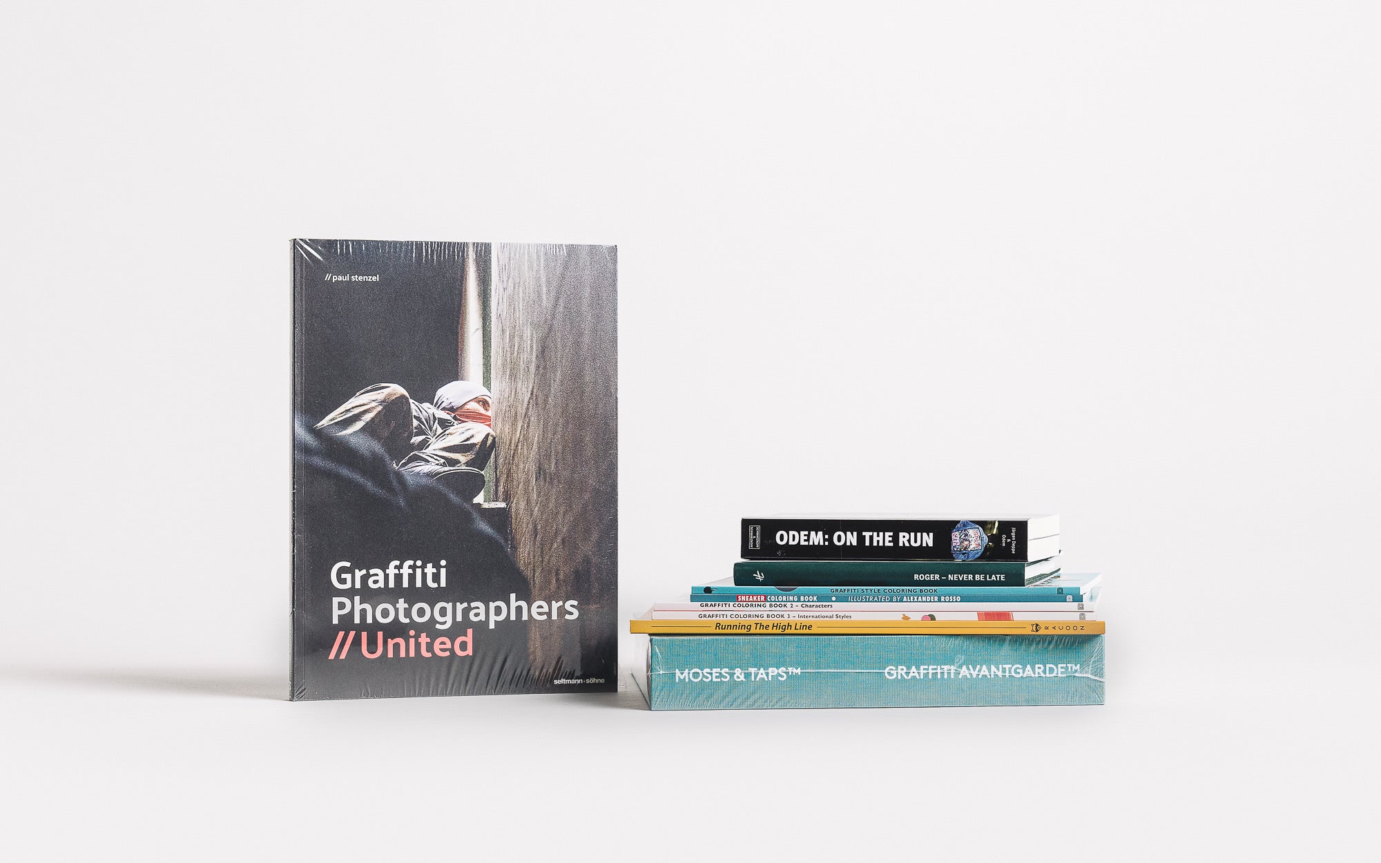 A single graffiti book on a white table next to a pile of books.