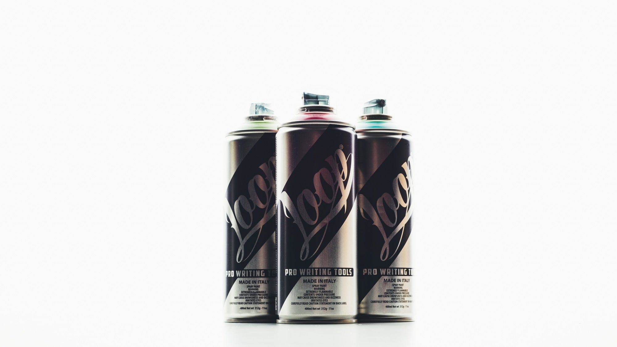  Three colorful spray Loop cans on a white surface. Ready to add a pop of color to any project.