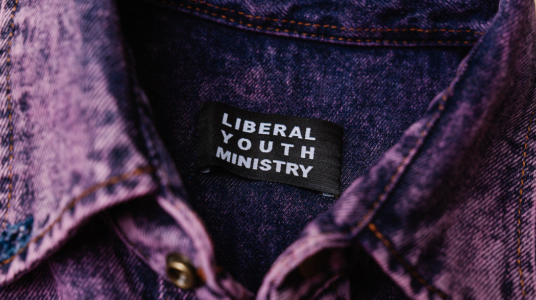 A stylish purple denim jacket with the label "Liberal Youth Ministry" on it. Perfect for making a statement!