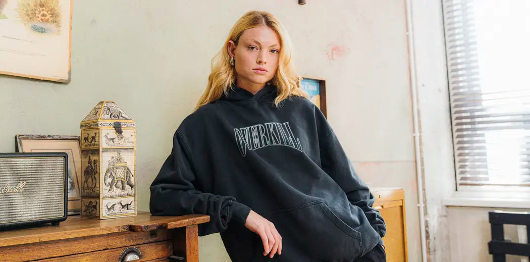 A woman in a black sweatshirt sitting on a table.