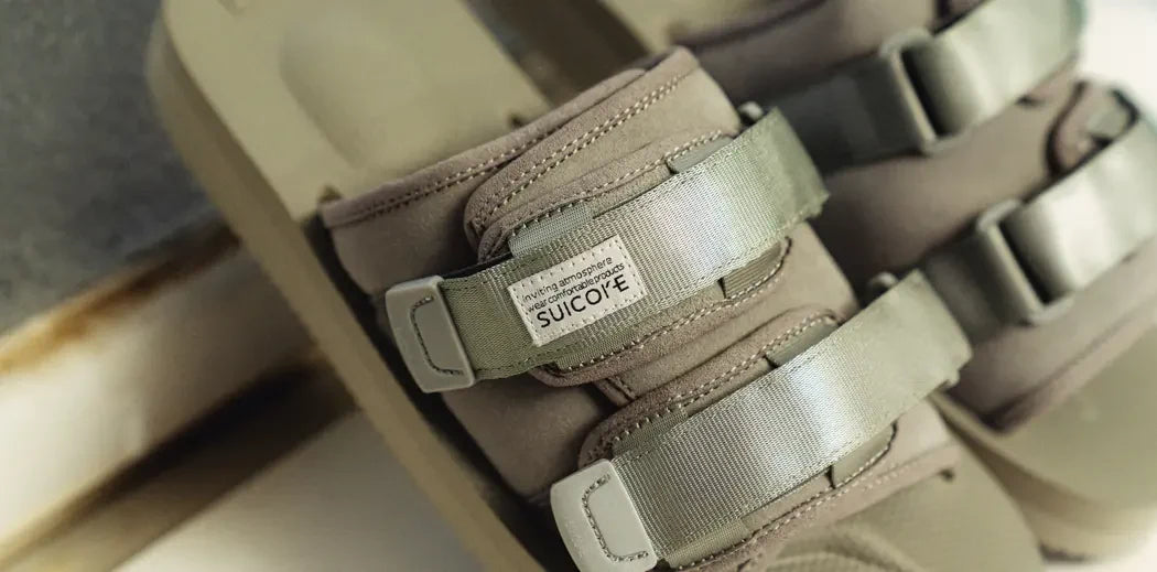 Grey Suicoke slides with straps.