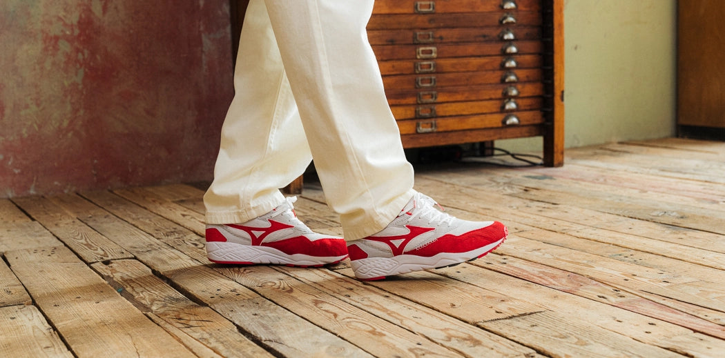A person wearing white pants and Mizuno sneakers.
