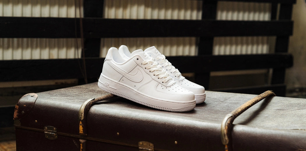 Someone lacing up white Nike Air Force 1 shoes