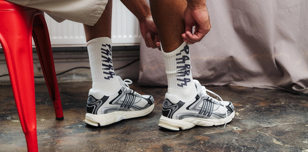 A guy wearing whitesocks, pulling them up. Perfect for men's underwear, these white socks are a must-have!