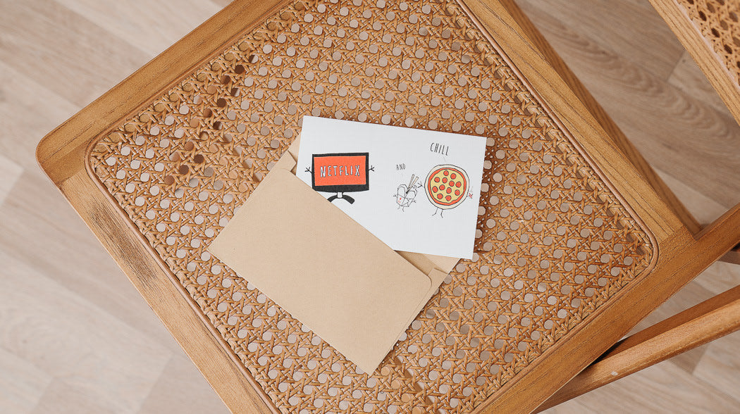 Wooden chair with pizza and card on seat by Nocturnal Paper.