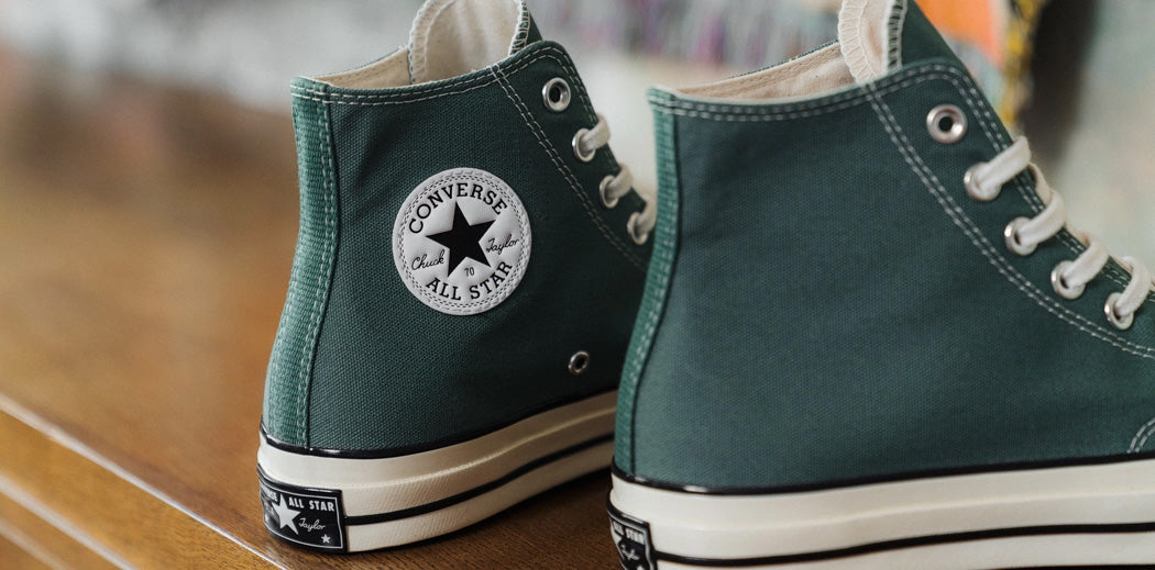 A pair of green Converse Chucks placed on the foor.